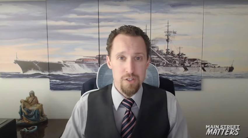 Der Ökonom E.J. Antoni wird vor einem Kunstwerk, das das Nazi-Kriegsschiff Bismarck zeigt, interviewt.